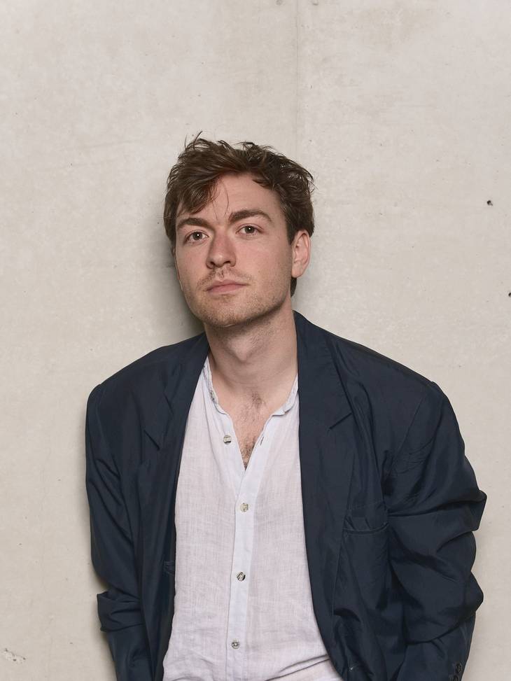 Foto  eines Mannes mit dunklen Jacket und weißen Hemd.