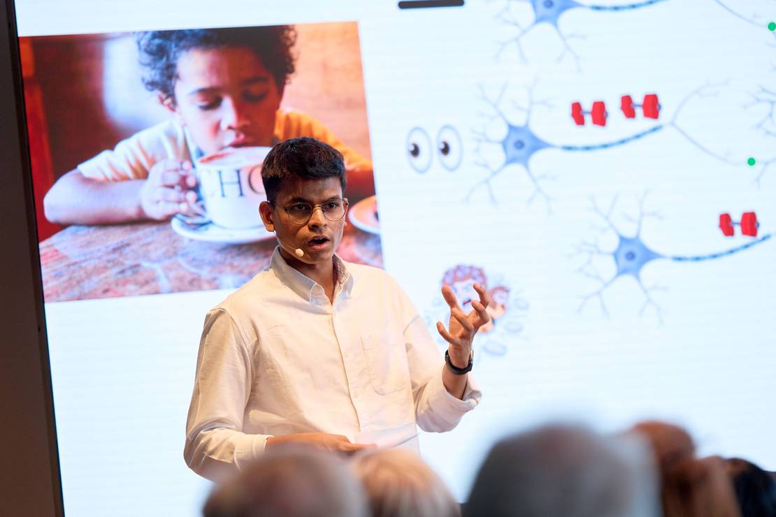 Foto eines jungen Mannes, der zum Publikum spricht.