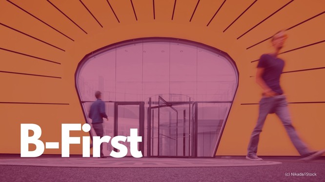 Foto von einem Eingang mit Drehtür, darüber liegt ein rotes Overlay mit dem Text: B-First.