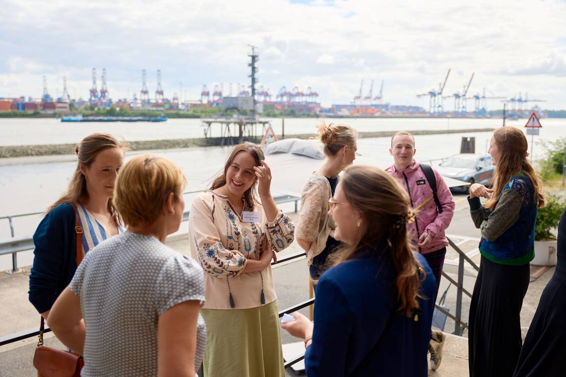 Das Team der Stiftung unterhält sich. Sie stehen draußen auf der Hafenkante.