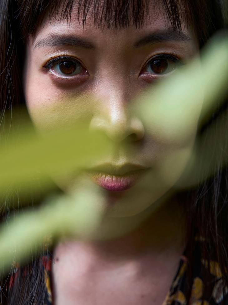 Porträtfoto von Mai Linh, im Vordergrund verwischt ein Zweig, dahinter ihr Gesicht.